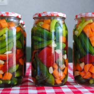 Three jars of assorted pickled vegetables on a red checkered tablecloth.